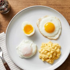 Assiette montrant différentes cuissons d’œufs : œuf au plat, œuf poché, œuf mollet coupé et œufs brouillés.