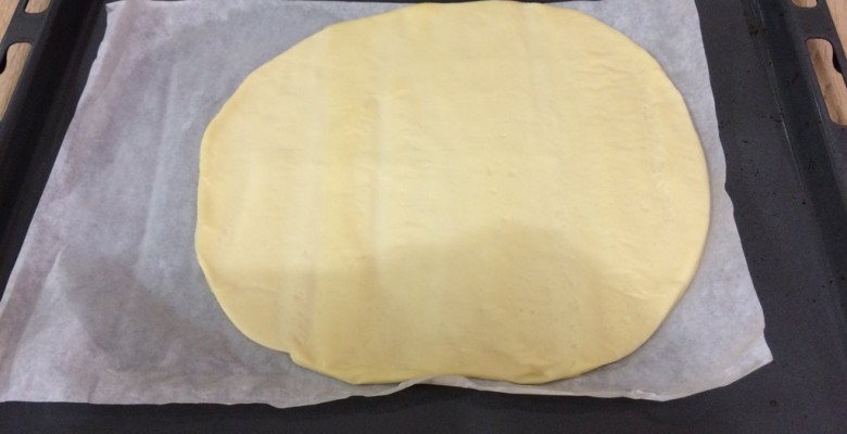 Déroule ou étale la pâte à pizza sur un papier cuisson sulfurisé
